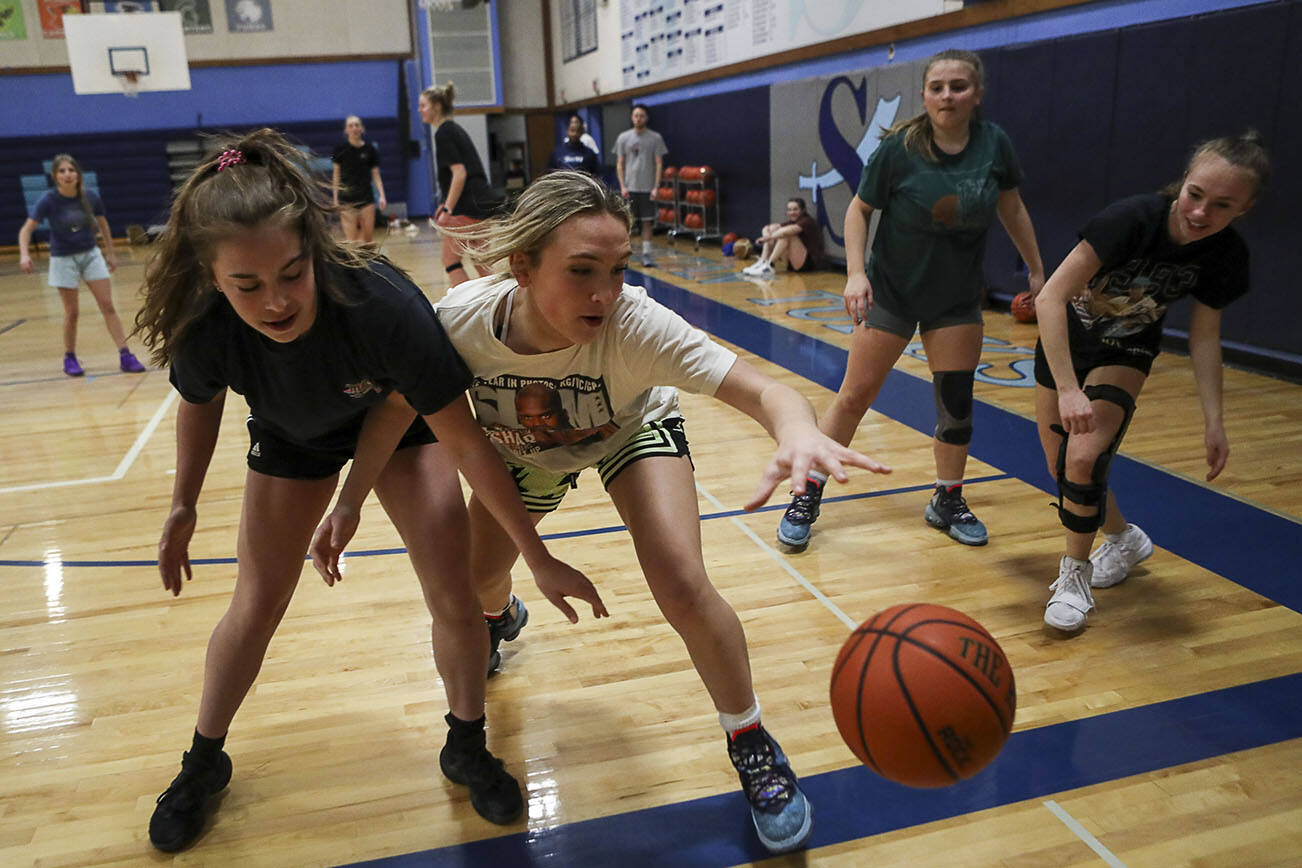 Wendy Asper (4), left, and Taylor Cushing (3), right, reach for the ball during a girls basketball practice at Sultan High School in Sultan, Washington on Thursday, Feb. 23, 2023. The Turks made the state playoffs for the first time in program history. (Annie Barker / The Herald)