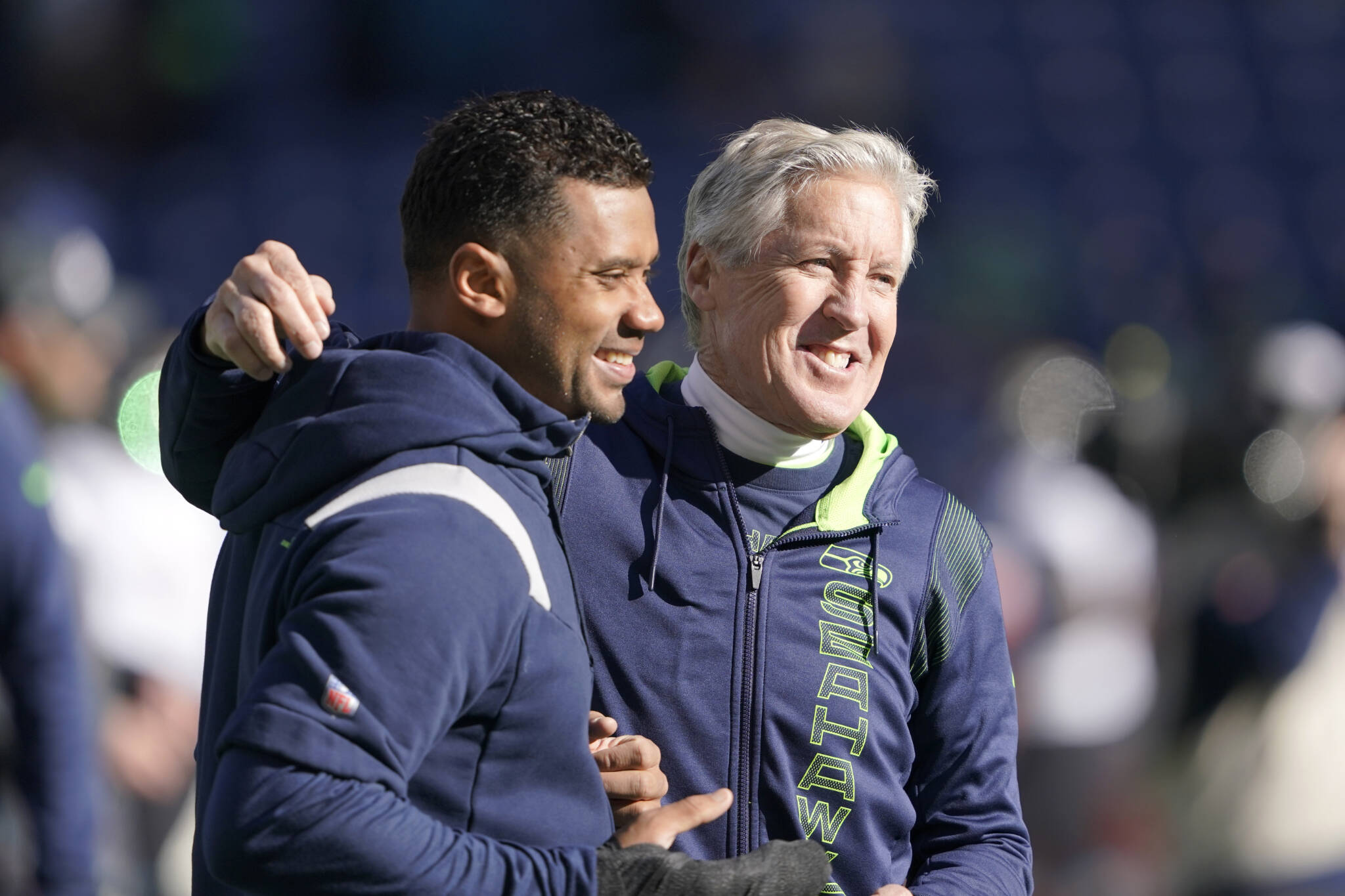 Seahawks head coach Pete Carroll (right) throws his arm around injured quarterback Russell Wilson as they walk on the field before a game against the Jaguars Oct. 31, 2021, in Seattle. (AP Photo/Ted S. Warren)