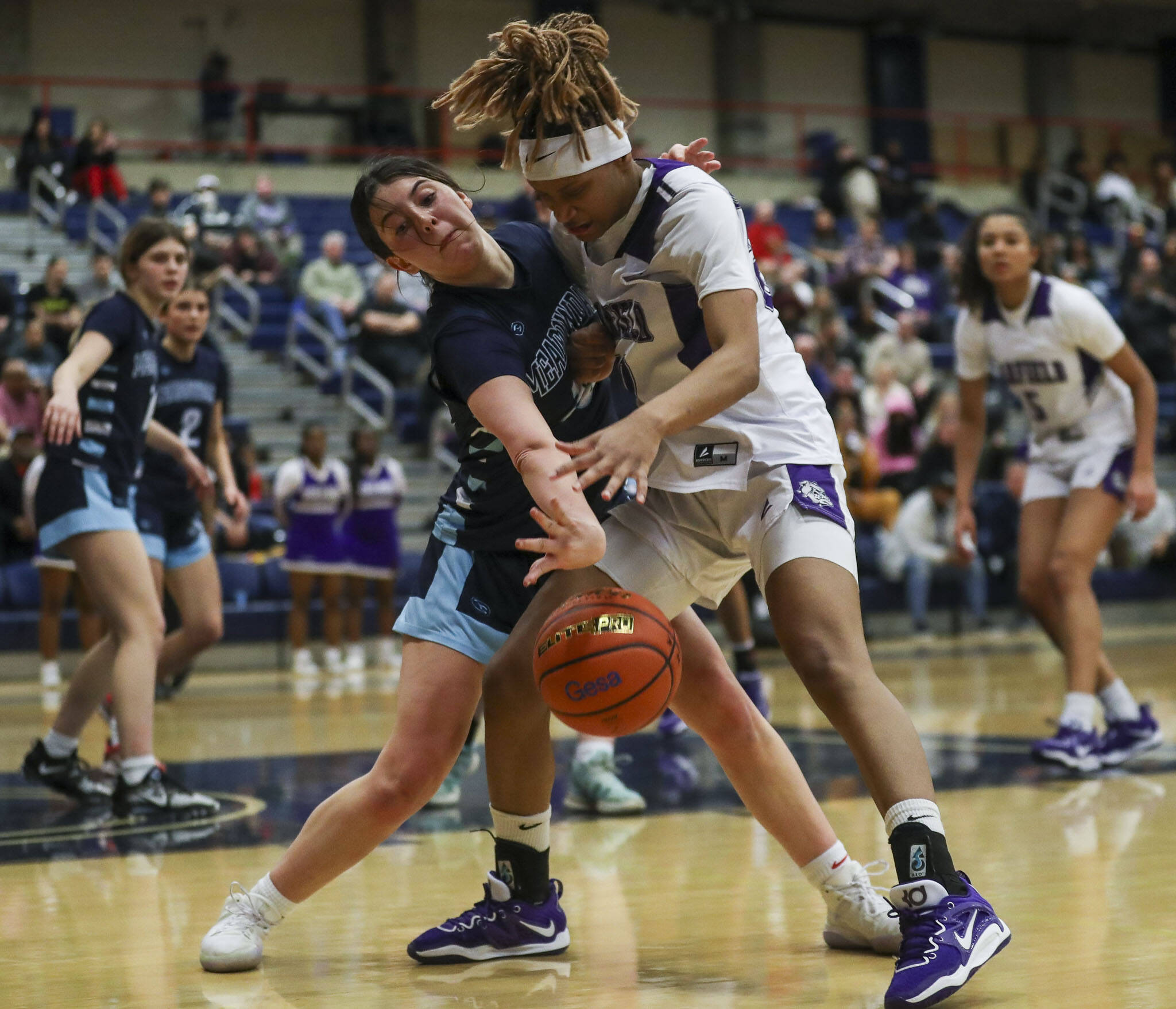 Meadowdale’s Natalie Durbin (10) and Garfield’s Rakiyah Jackson (20) fight for the ball during a 3A girls basketball state regional game at the Courter Family Athletic Pavilion in Bellevue on Friday. Garfield won 62-48. (Annie Barker / The Herald)
