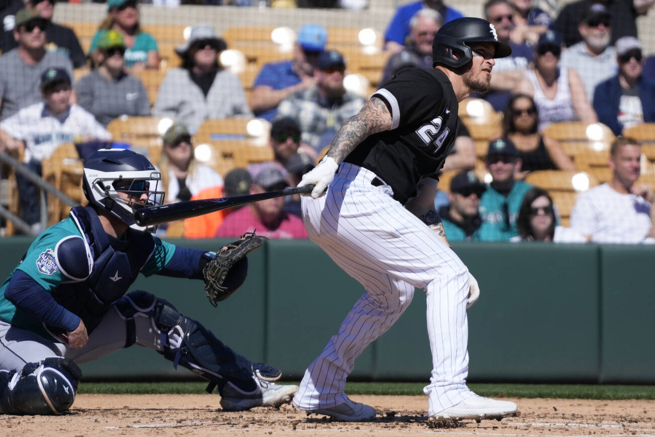 Chicago White Sox's Yasmani Grandal (24) watches the flight of his single as Seattle Mariners catcher Brian O'Keefe looks on during the second inning of a spring training baseball game Monday, Feb. 27, 2023, in Phoenix. (AP Photo/Ross D. Franklin)