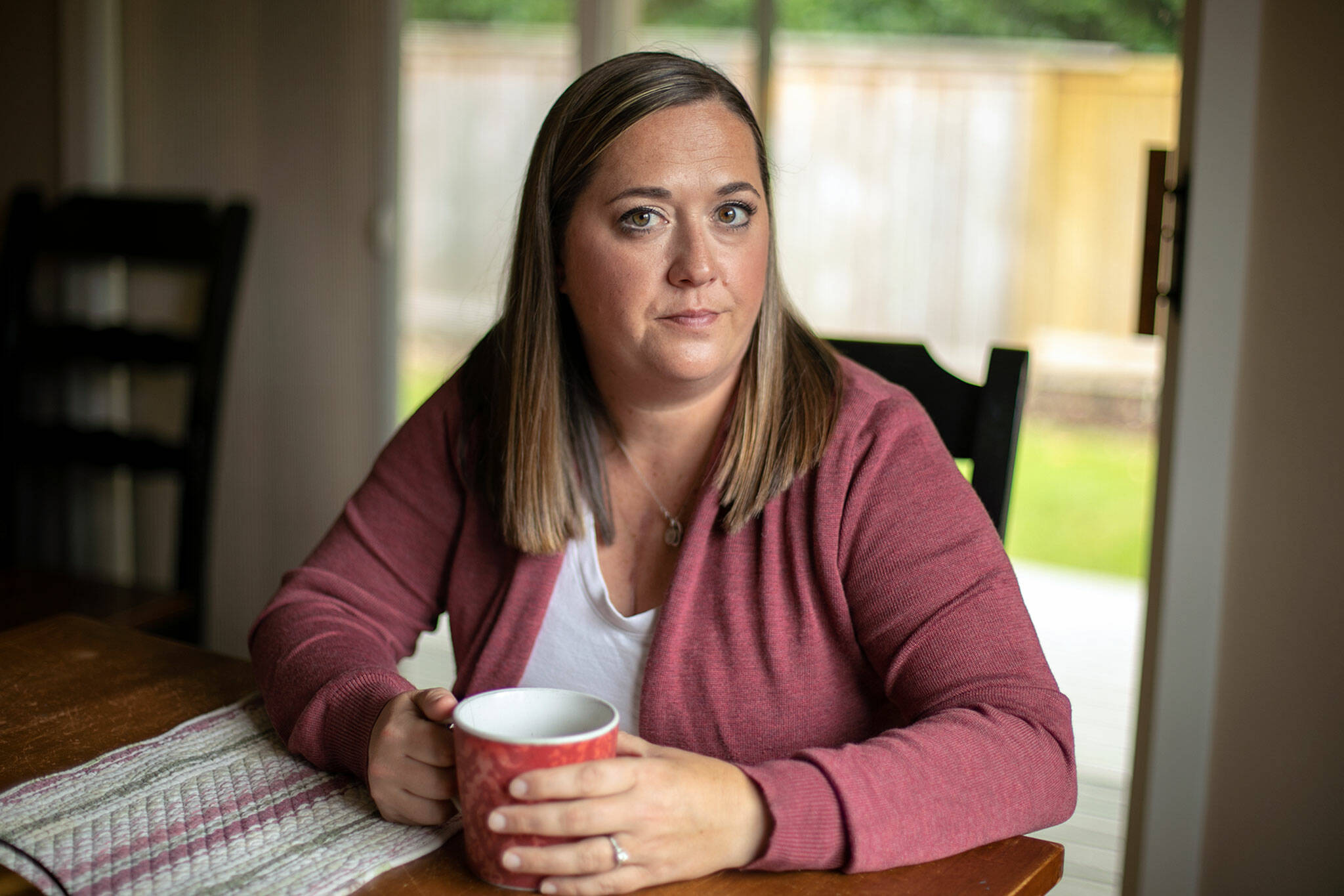 Marie Riley, 42, sits in her dining room with a cup of tea on Oct. 25, at her family’s home in North Bend. Riley was born with tetralogy of fallot, a rare congenital heart condition that has required multiple open-heart surgeries during her lifetime. (Ryan Berry / The Herald)