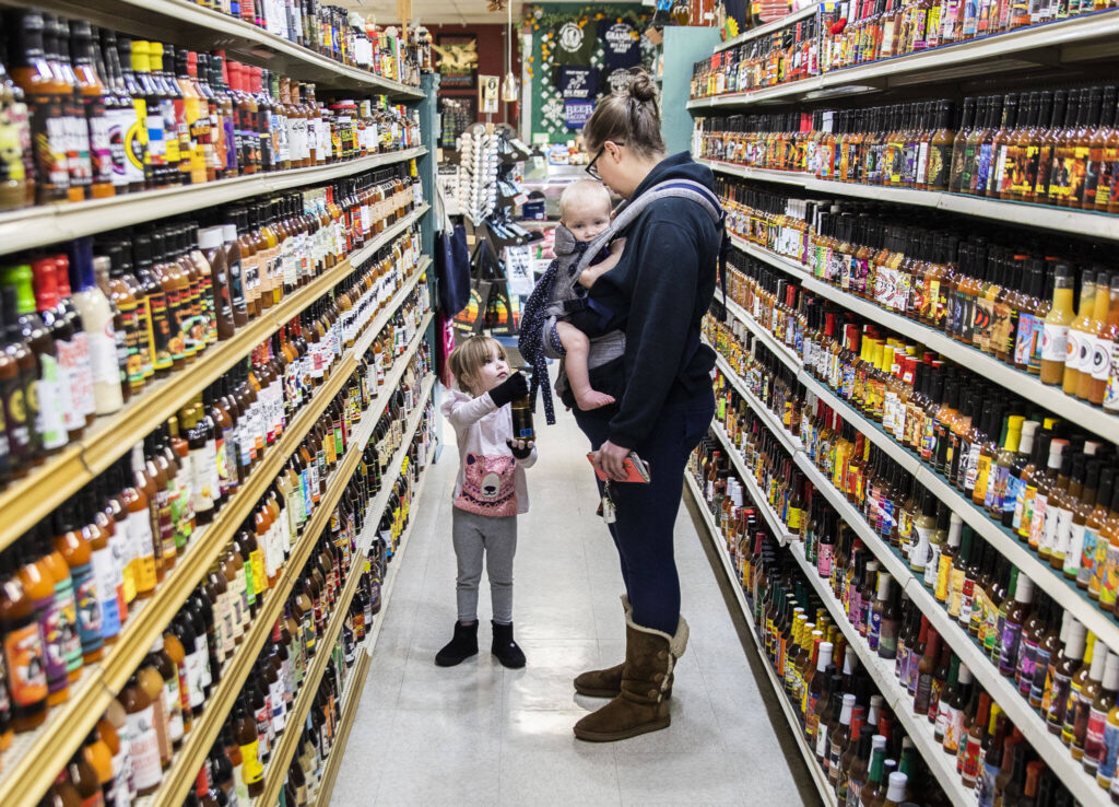 Elizabeth Ferrari, left, hands her mom Noelle Ferrari her choice of hot sauce from the large selection at Double DD Meats in Mountlake Terrace. (Olivia Vanni / The Herald)
