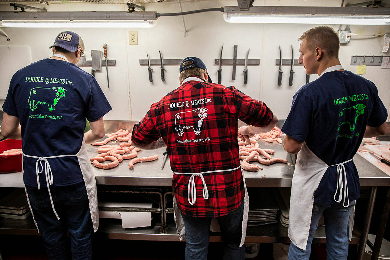 Logan Leadley, Kyle Thies and Justin Nygard work on tying sausages at Double DD Meats on Wednesday, Jan. 11, 2023 in Mountlake Terrace, Washington. (Olivia Vanni / The Herald)