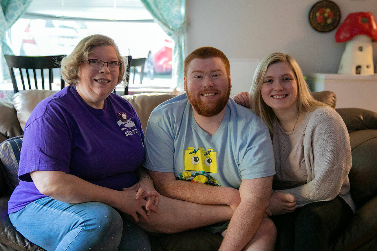 Mae Hochstetler, left, sits with her twin children Joshua and Joy Hochstetler, both 25, at her home where she lives with Joshua on Friday, Feb. 24, 2023, in Lynnwood, Washington. (Ryan Berry / The Herald)