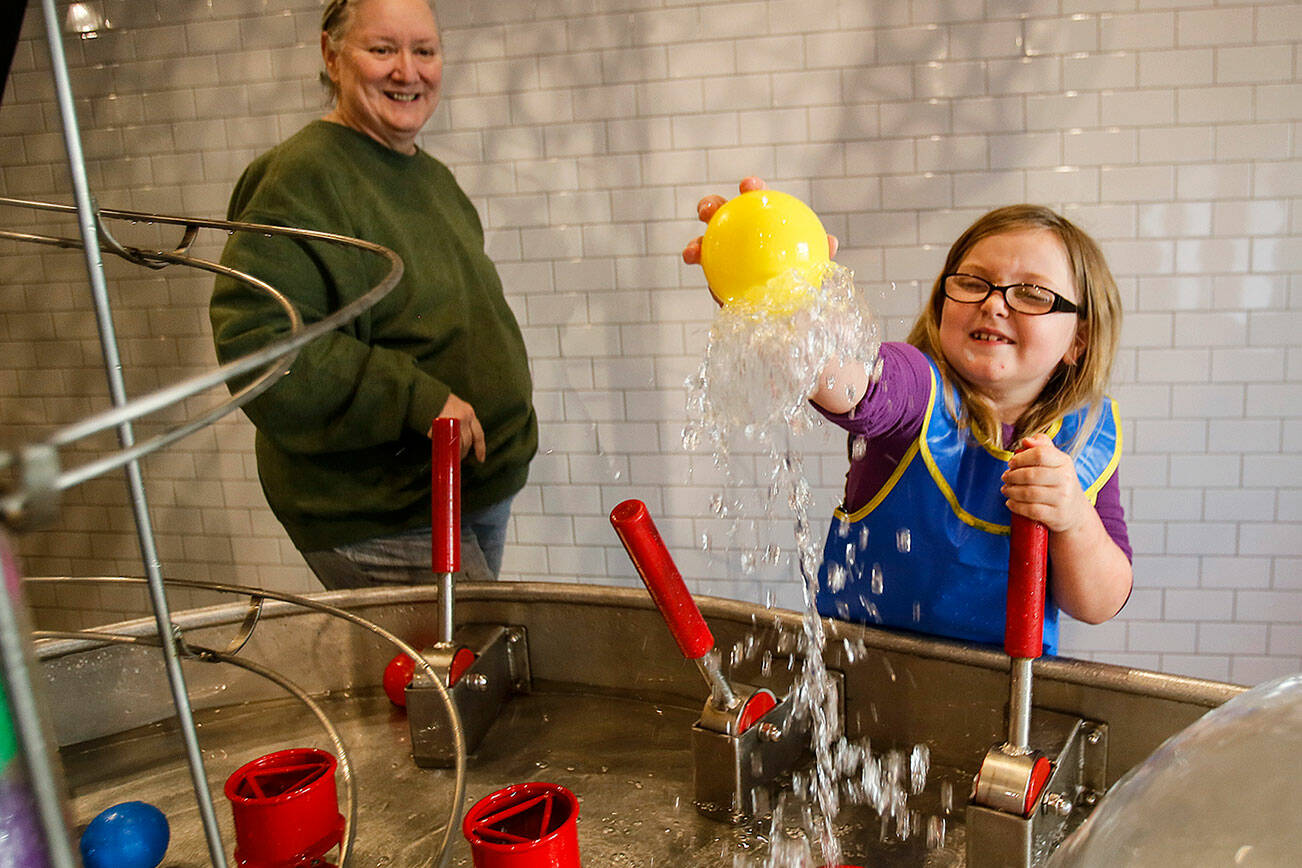 Dan Bates / The Herald
With "adopted grandmother" Michele Tanis at her side, Madison Davis, 6, of Snohomish reacts upon discovering she can reach into an air pocket inside a water feature, Wednesday, at the Imagine Children's Museum in Everett.