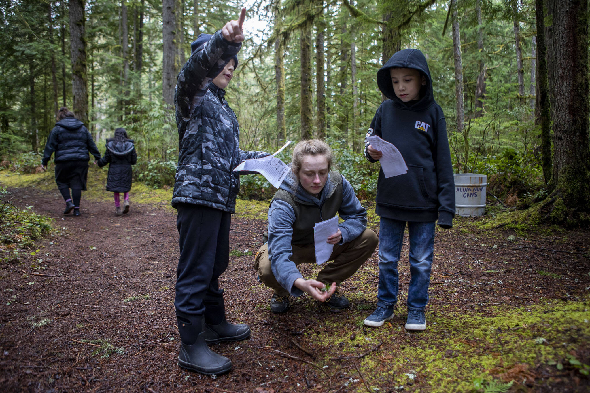 Sebastian Sanchez, left, instructor Hannah Dreesbach, center, and Kash Willis, right, learn how to identify trees near Darrington Elementary School on Feb. 17 in Darrington. Environmental and outdoor education lessons are woven throughout the in-school and after-school activities in this small community, thanks to the Glacier Peak Institute. The non-profit arose from community concerns in the wake of the Oso landslide disaster. (Annie Barker / The Herald)