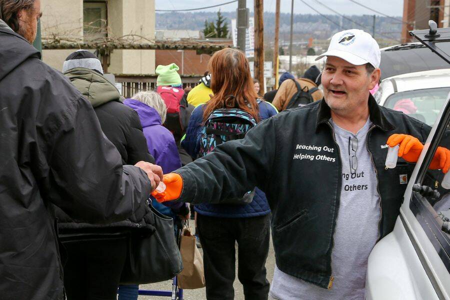 Robert Smiley of The Hand Up Project hands out hand sanitizer in downtown Everett on March 26, 2020. (Kevin Clark / The Herald)