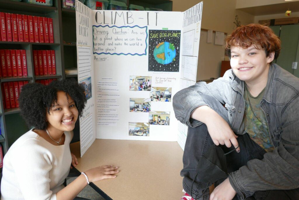 Maplewood Parent Cooperative eighth graders Maedot Yoseph, left, and M.J. Pankow, with their class project poster on Feb. 22 in Edmonds. (Julie Titone / The Herald)
