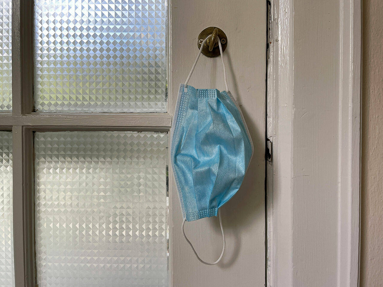A protective mask hanging on a front door. (Chuck Taylor / The Herald)