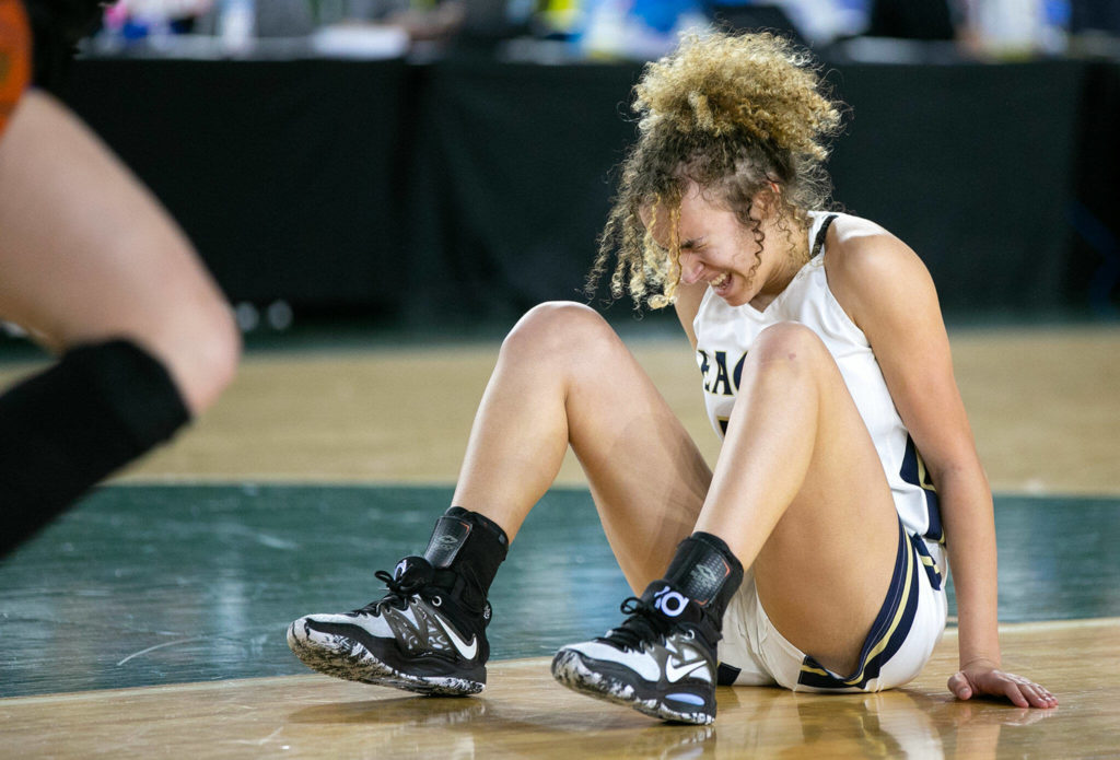 Arlington’s Samara Morrow winces while getting up after hitting the ground hard on a loose ball against Lake Washington in the 3A semifinal on Friday, March 3, 2023, at the Tacoma Dome in Tacoma, Washington. (Ryan Berry / The Herald)
