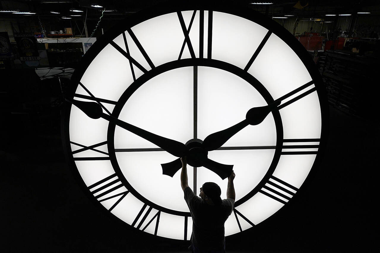 Electric Time technician Dan LaMoore adjusts a clock hand on a 1,000-pound, 12-foot diameter clock constructed for a resort in Vietnam, March 9, 2021, in Medfield, Mass. Daylight saving time begins at 2 a.m. local time Sunday, March 12, when clocks are set ahead one hour. (Elise Amendola / Associated Press)