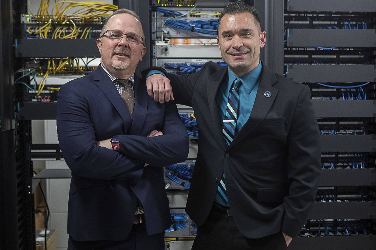 Everett Public Schools chief information officer Brian Beckley, left, and state coordinator for the Cybersecurity and Infrastructure Security Agency (CISA) Ian Moore, right, pose for a photo in the server room at the Everett Public Schools Community Resource Center in Everett, Washington on Tuesday, March 21, 2023. (Annie Barker / The Herald)