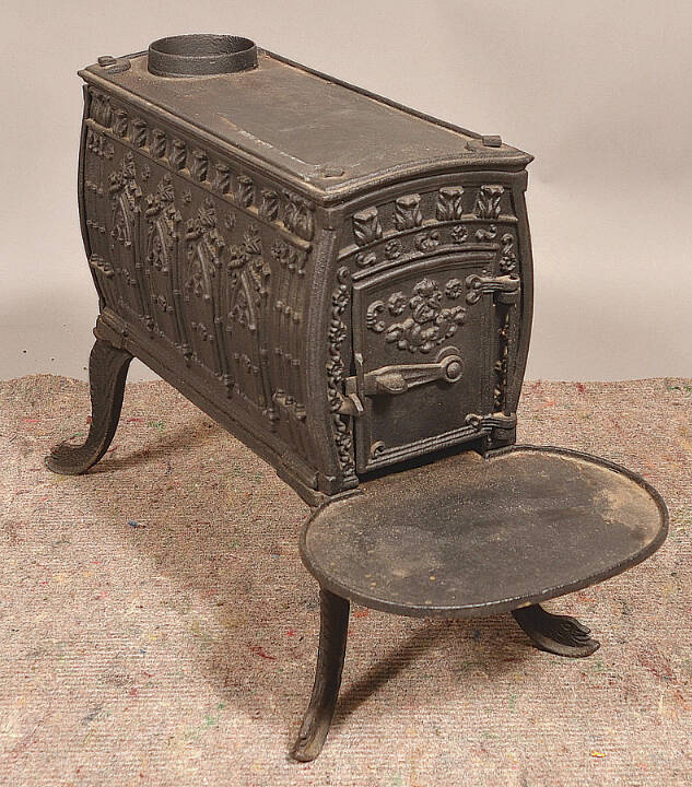 This cast-iron wood stove kept a 19th-century room warm. Its embossed designs, especially the rows of pointed arches on its sides, were meant to evoke medieval architecture.