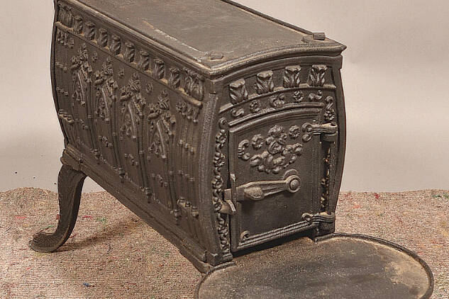 This cast-iron wood stove kept a 19th-century room warm. Its embossed designs, especially the rows of pointed arches on its sides, were meant to evoke medieval architecture.