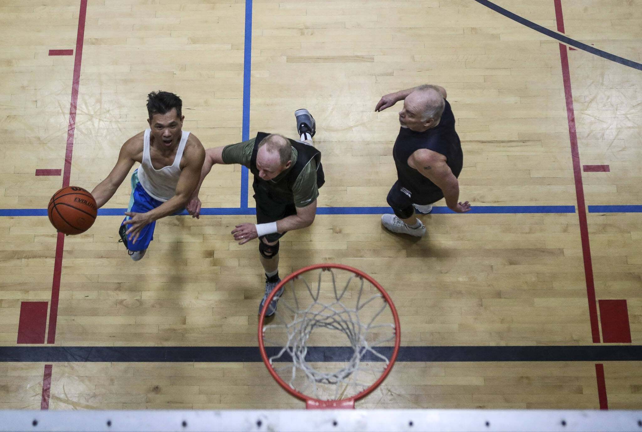 Nome McCaffrey, 57, left, moves with the ball during a pick-up basketball game at the Marysville YMCA in Marysville, Washington, on Monday, March 13, 2023. (Annie Barker / The Herald)