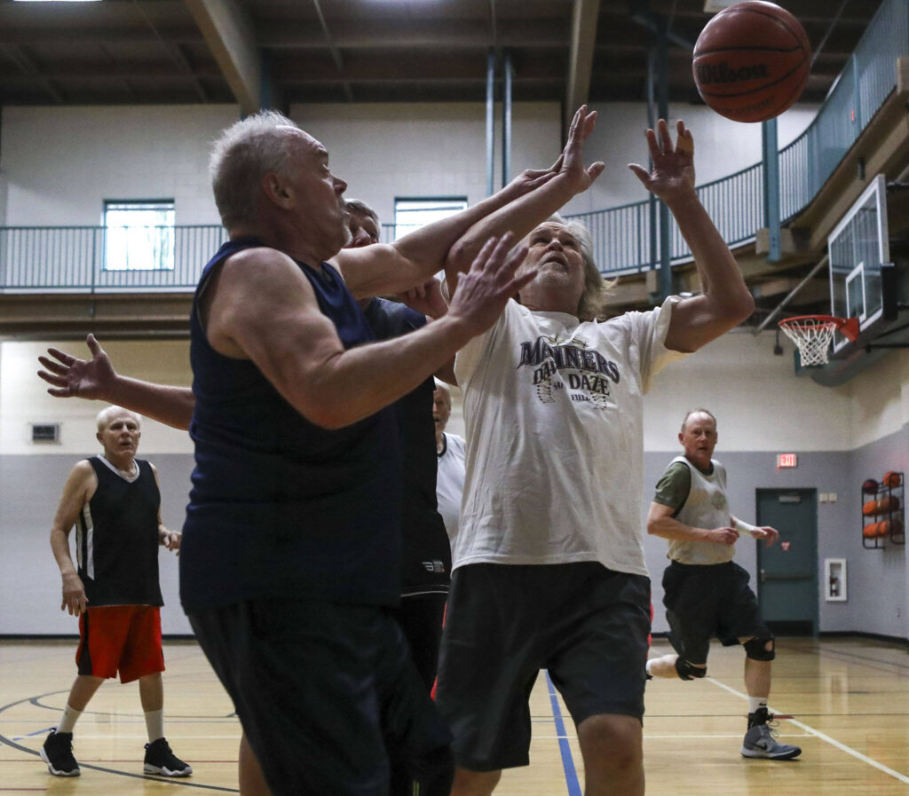 Steve Powell, 66, left, and Mac Sheridan, 70, fight for the ball during a pick-up basketball game at the Marysville YMCA in Marysville, Washington, on Monday, March 13, 2023. (Annie Barker / The Herald)
