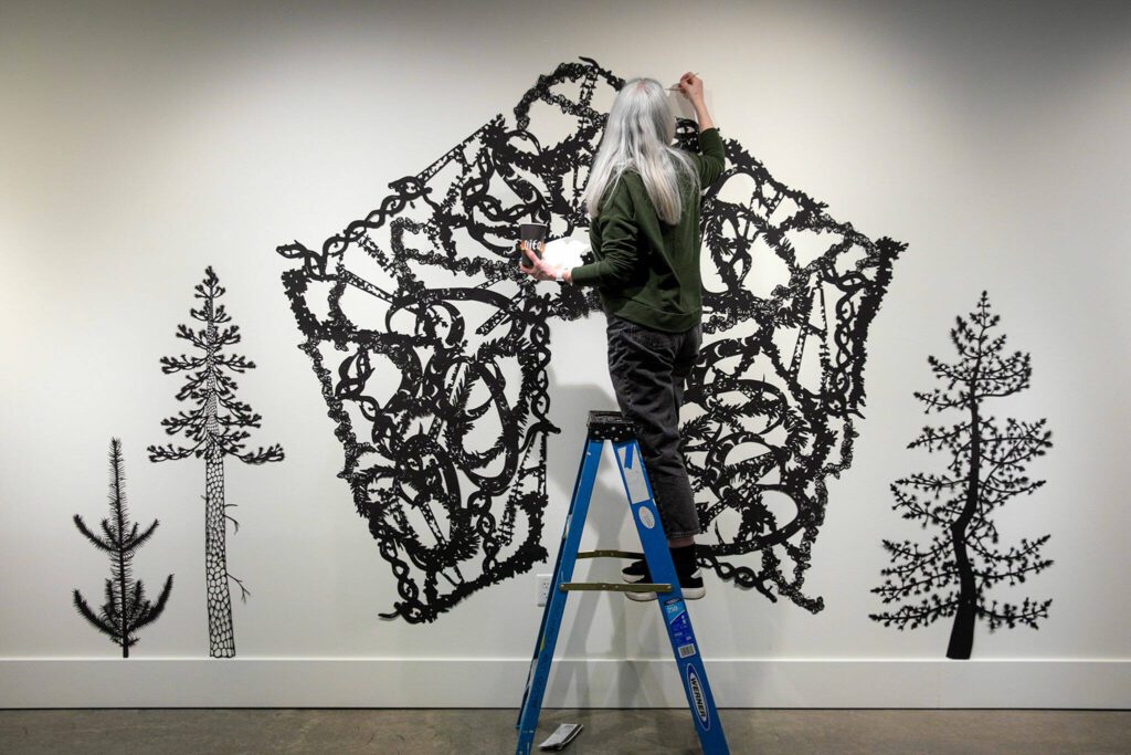 Artist Ann Chadwick Reid puts the finishing touches on a delicate piece called “Solastalgia” during the setup for Exploring The Edge at Schack Art Center on Sunday, March 19, 2023, in Everett, Washington. (Ryan Berry / The Herald)
