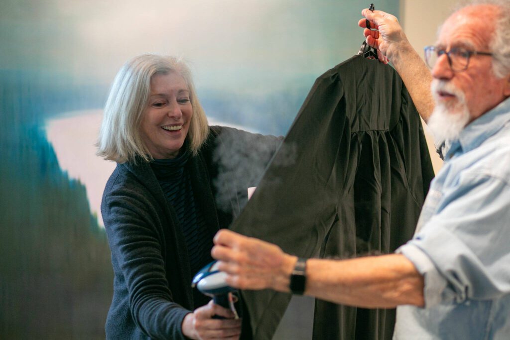 Meg Holgate, with the helping hand of fellow guest curator Steve Klein, steams a set of judicial robes while working on some of the more detailed work of installing A Precarious Edge at Schack Art Center on Sunday, March 19, 2023, in Everett, Washington. (Ryan Berry / The Herald)
