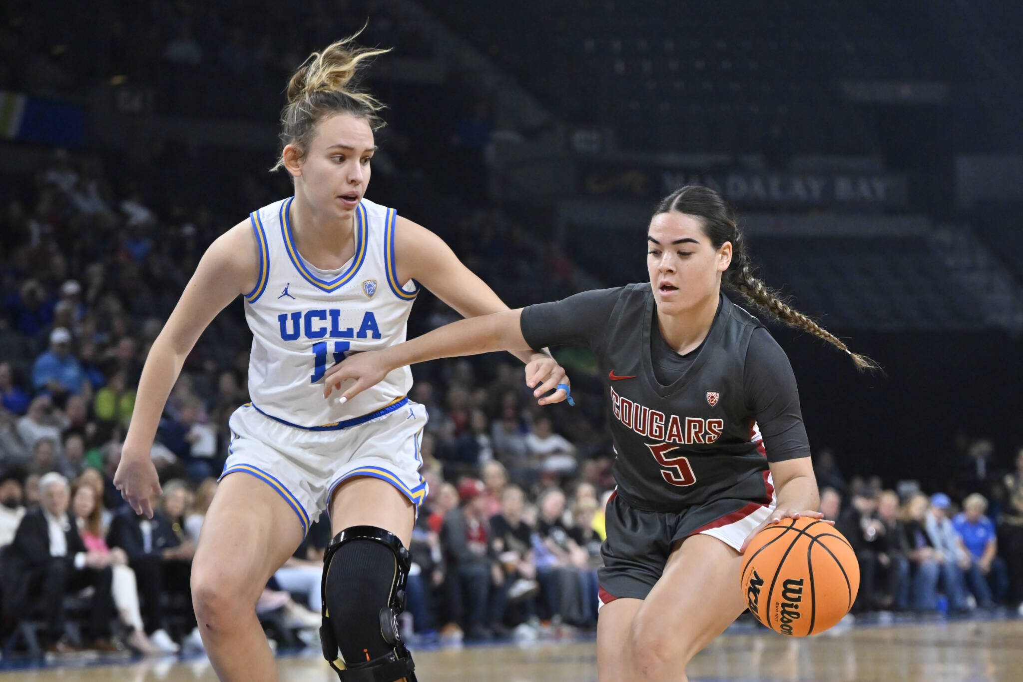 Washington State guard Charlisse Leger-Walker (right) dribbles past UCLA’s Emily Bessoir during the finals of the Pac-12 women’s tournament on March 5 in Las Vegas. (AP Photo/David Becker)