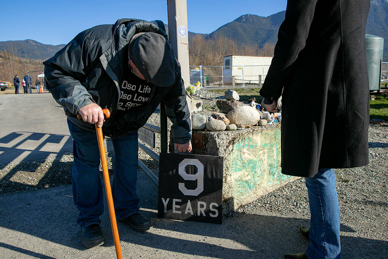 Ron Thompson, a former resident of Steelhead Haven, places a sign marking the 9-year anniversary of the Oso landslide Wednesday, March 22, 2023, at the landslide memorial site in Oso, Washington. (Ryan Berry / The Herald)