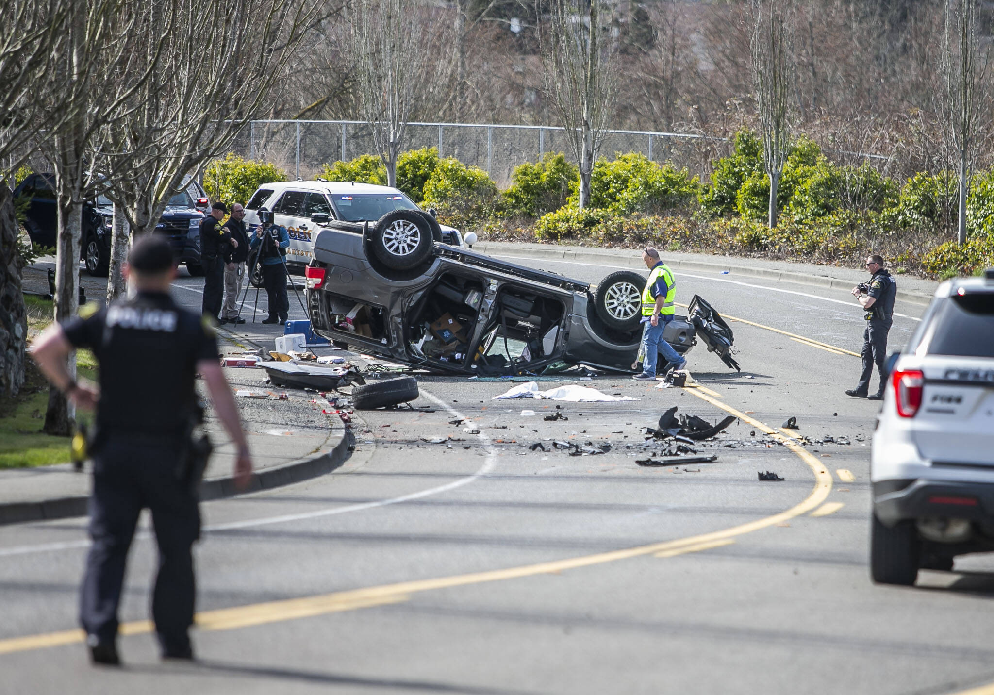 Police walk around the scene of a car crash along Ingraham Boulevard on Friday, March 17, 2023, in Marysville, Washington. (Olivia Vanni / The Herald).