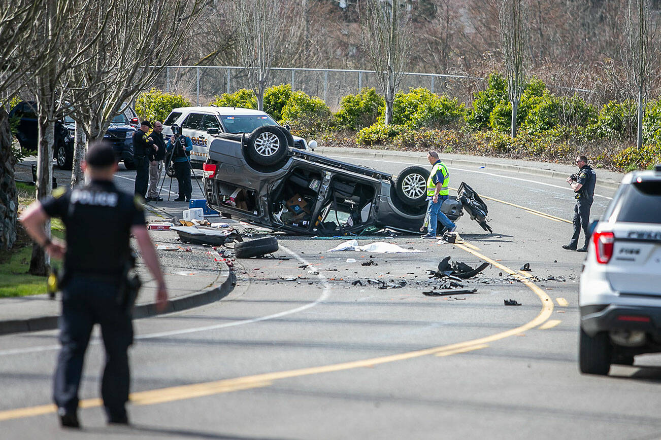 Police walk around the scene of a car crash along Ingraham Boulevard on Friday, March 17, 2023 in Marysville, Washington. (Olivia Vanni / The Herald).