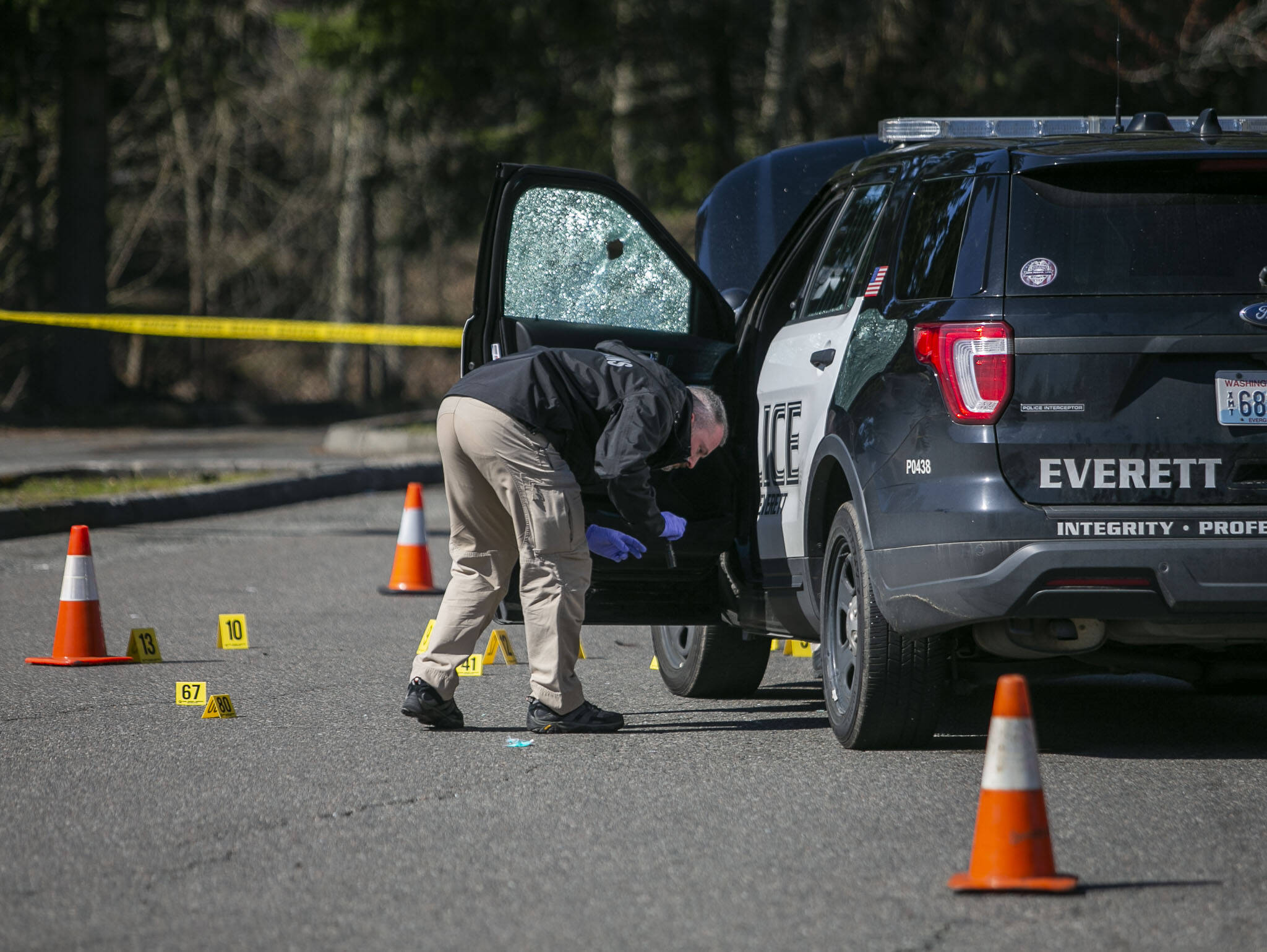 A crime scene investigator surveys the area around a police car that was involved in a shooting early Wednesday morning along Highway 99 that left one person dead. (Olivia Vanni / The Herald).