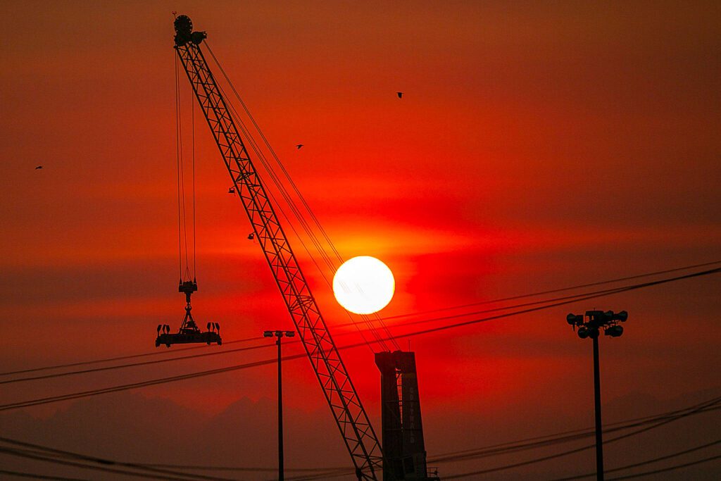 The sun turns a deep red as it sets beyond the Port of Everett and the Olympic Mountain Range on a hazardously smoky evening last October, in Everett. Following the start of the Bolt Creek Fire and other wildfires in the region, air quality in Snohomish County was frequently hazardous through September and October. (Ryan Berry / The Herald file photo)
