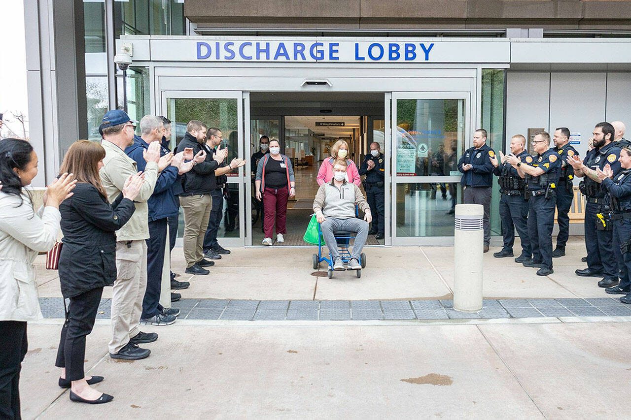 Everett police officers and civilian employees greet officer Chad House on Thursday, March 23, 2023, as he’s wheeled out of Providence Regional Medical Center Everett. (Everett Police Department)