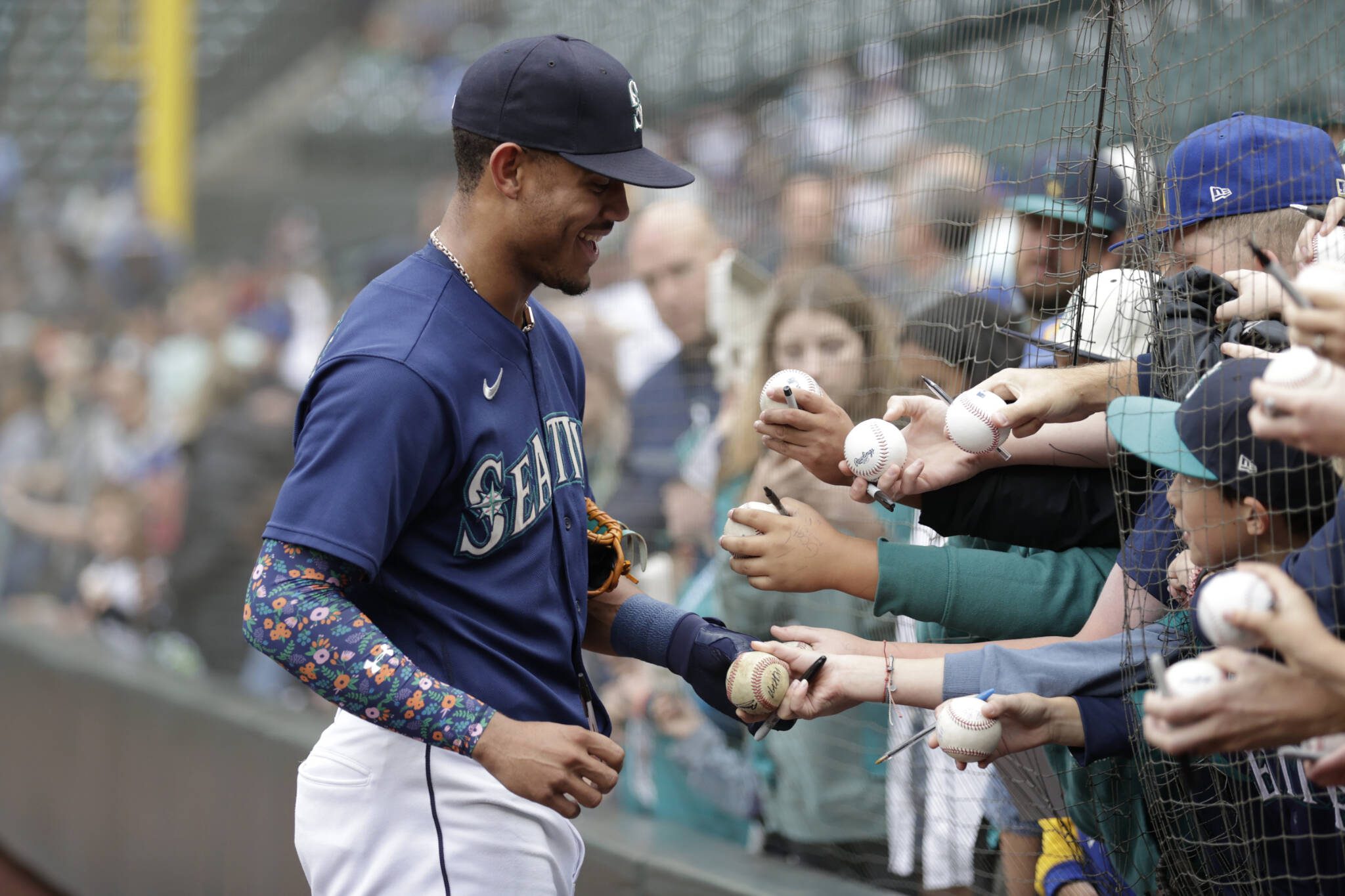 The Mariners’ Julio Rodriguez signs autographs for fans before a game against the Tigers on Oct. 5, 2022, in Seattle. (AP Photo/John Froschauer)