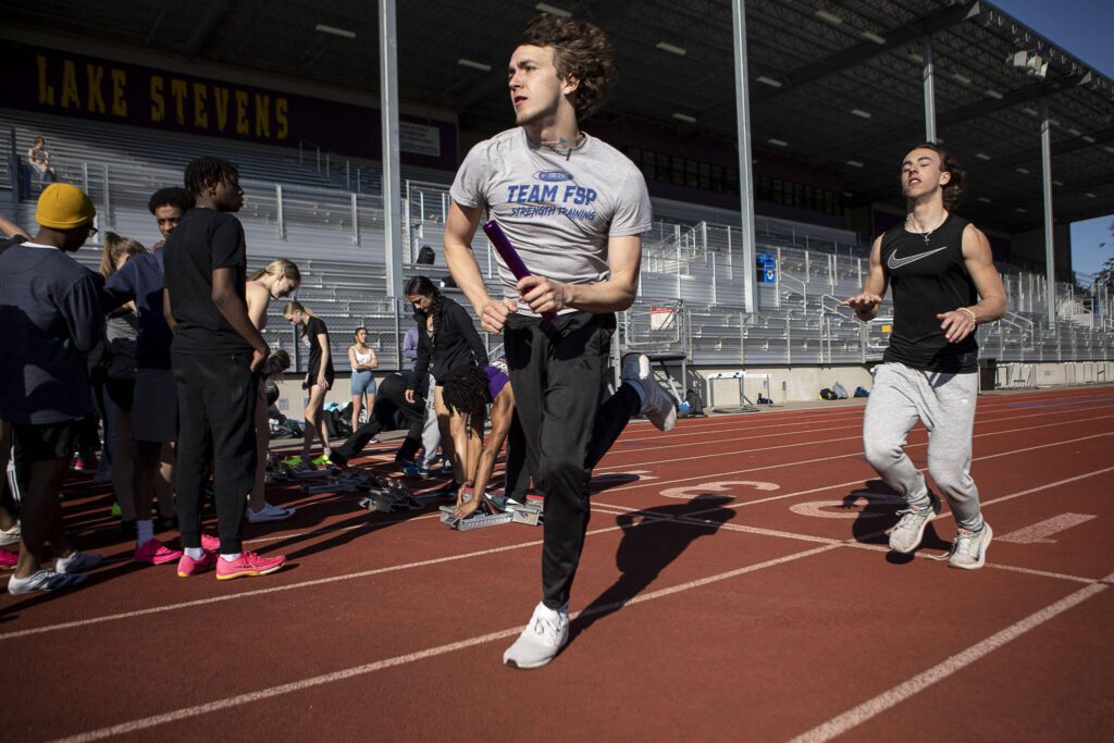 Relay racers practice next to sprinters during a track and field practice after school at Lake Stevens High School in Lake Stevens, Washington on Wednesday, March 22, 2023. The team has over 300 members. (Annie Barker / The Herald)
