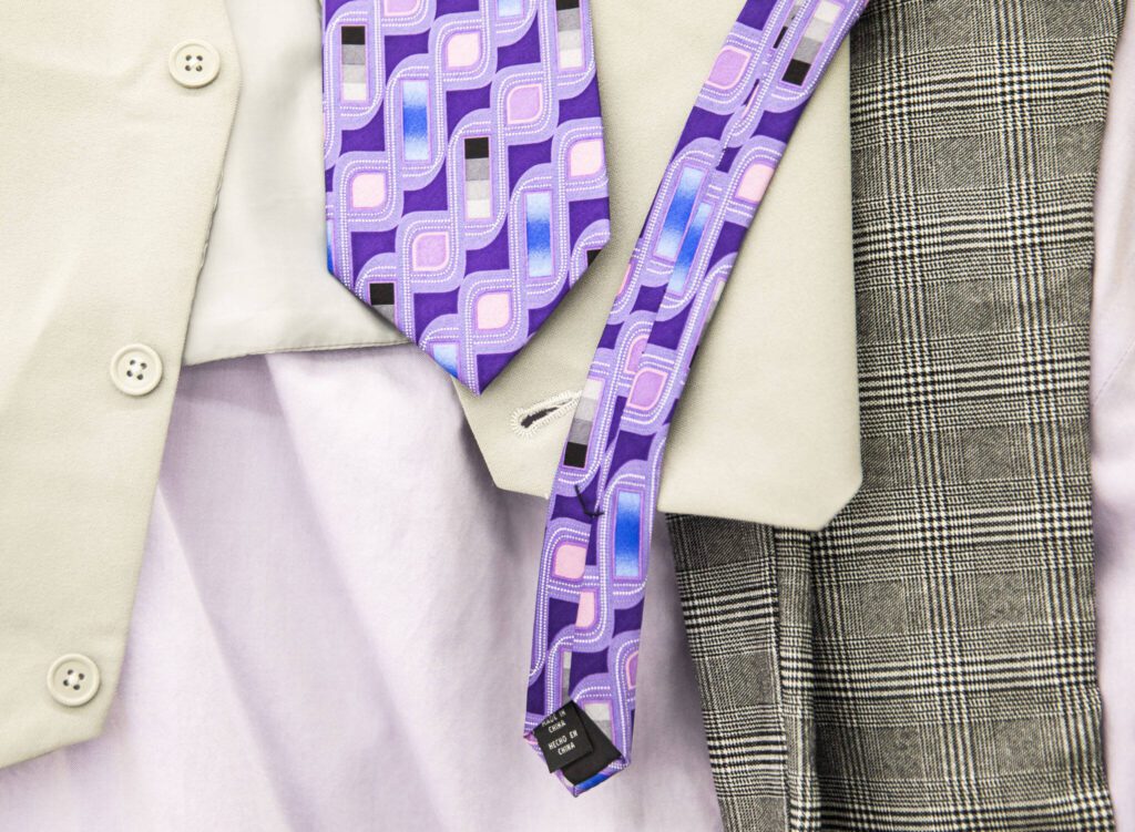 A multicolored tie paired with a lavender shirt, gray suit vest and patterned pants are layered on top of each other while Tim Lambright puts together a spring themed outfit at Value Village in Everett. (Olivia Vanni / The Herald)
