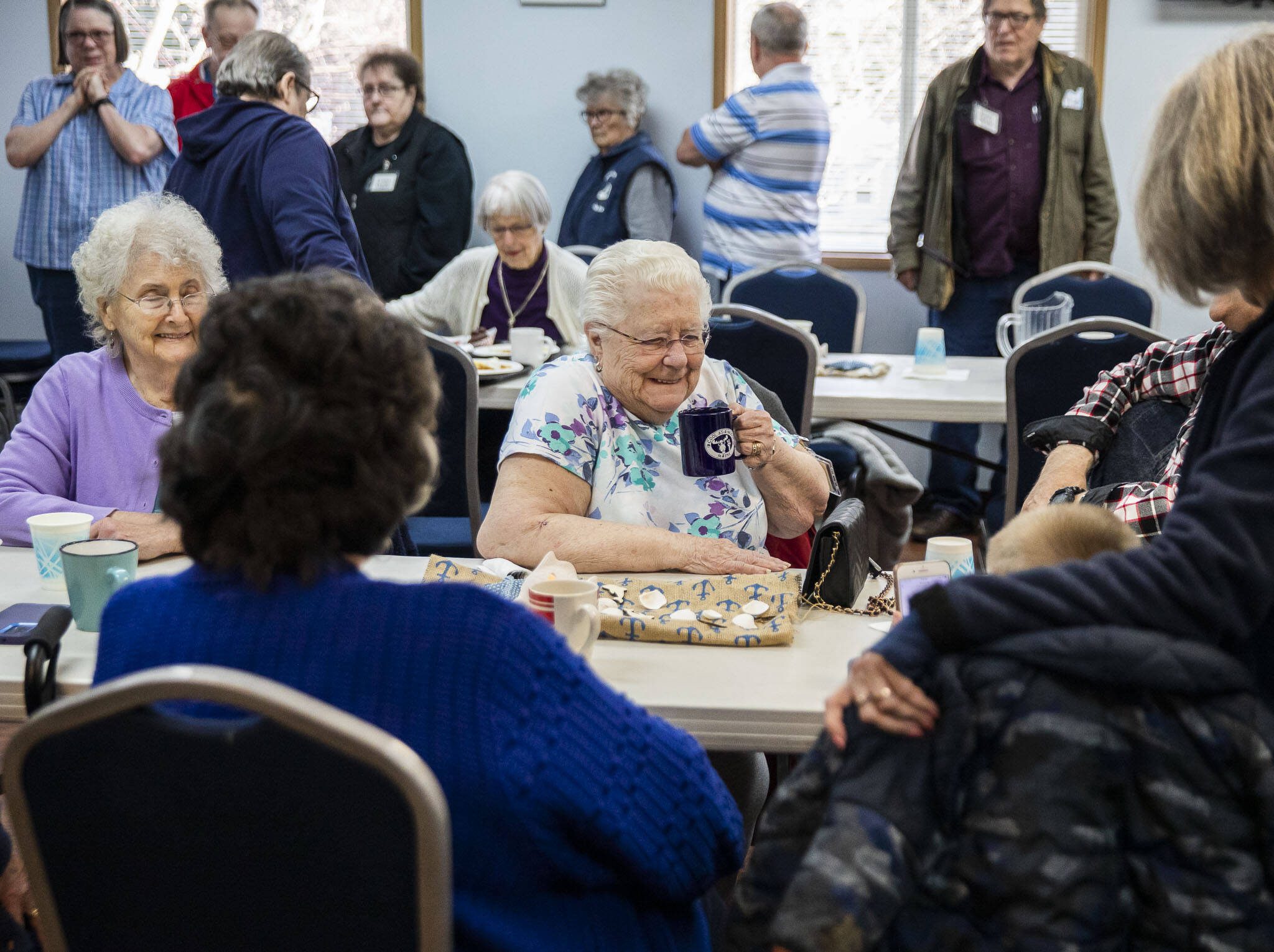 Arlene Petro sips coffee while people lineup for lunch at the Lake Stevens Senior Center on Wednesday, April 12, 2023 in Everett, Washington. (Olivia Vanni / The Herald)