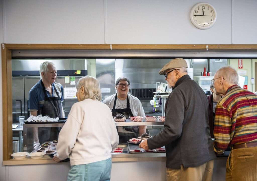 Mary O’Connor, center, laughs while chatting with people while they grab lunch at the Lake Stevens Senior Center on Wednesday, April 12, 2023 in Everett, Washington. (Olivia Vanni / The Herald)
