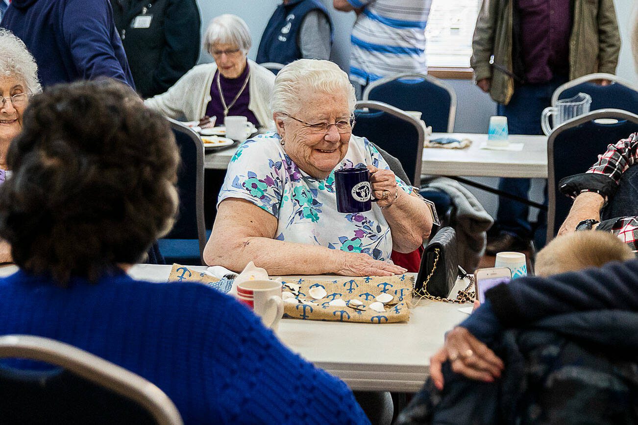 Arlene Petro sips coffee while people lineup for lunch at the Lake Stevens Senior Center on Wednesday, April 12, 2023 in Everett, Washington. (Olivia Vanni / The Herald)