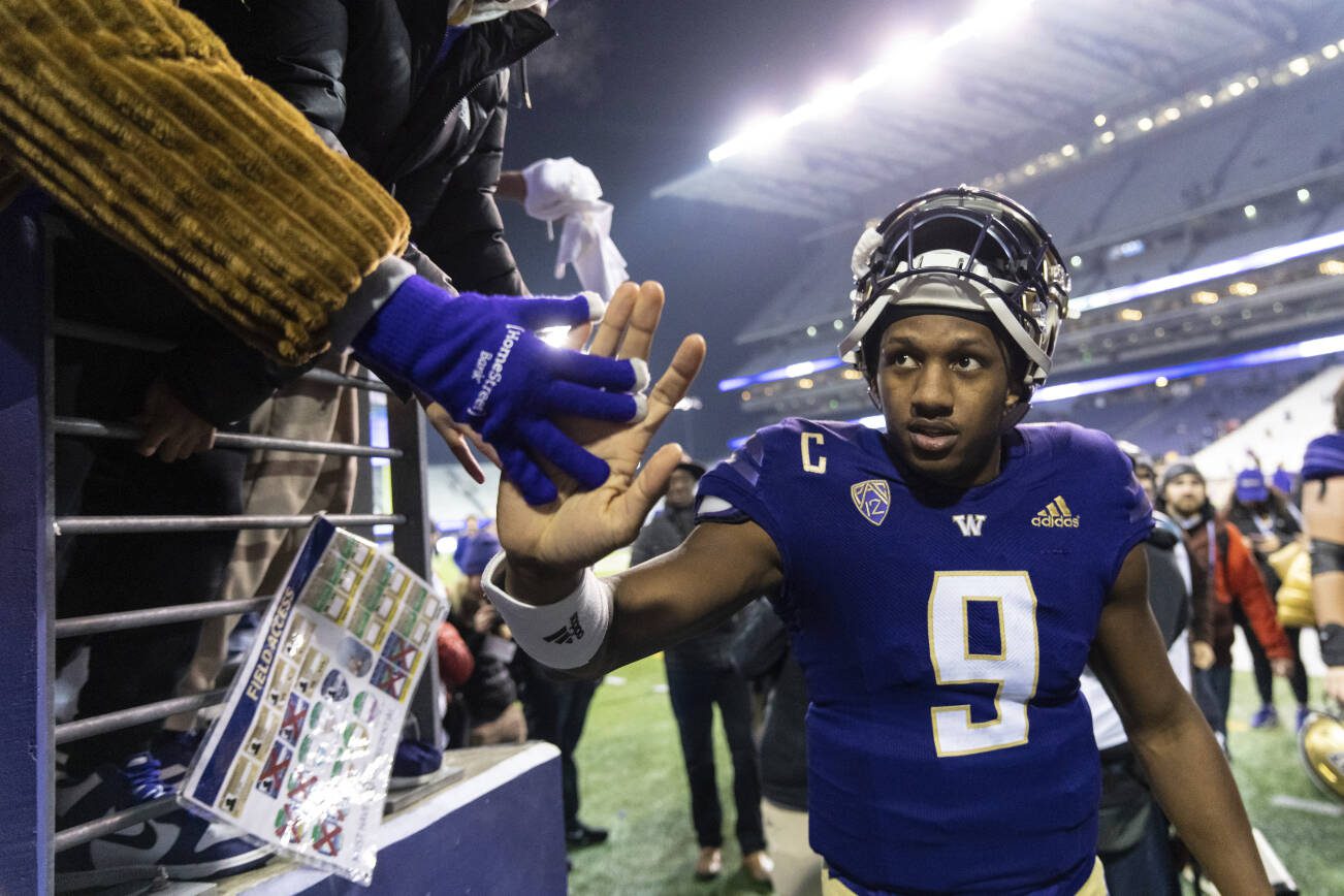 Washington quarterback Michael Penix Jr. high-fives a fan while leaving the field after the team's NCAA college football game against Colorado, Saturday, Nov. 19, 2022, in Seattle. Washington won 54-7. (AP Photo/Stephen Brashear)