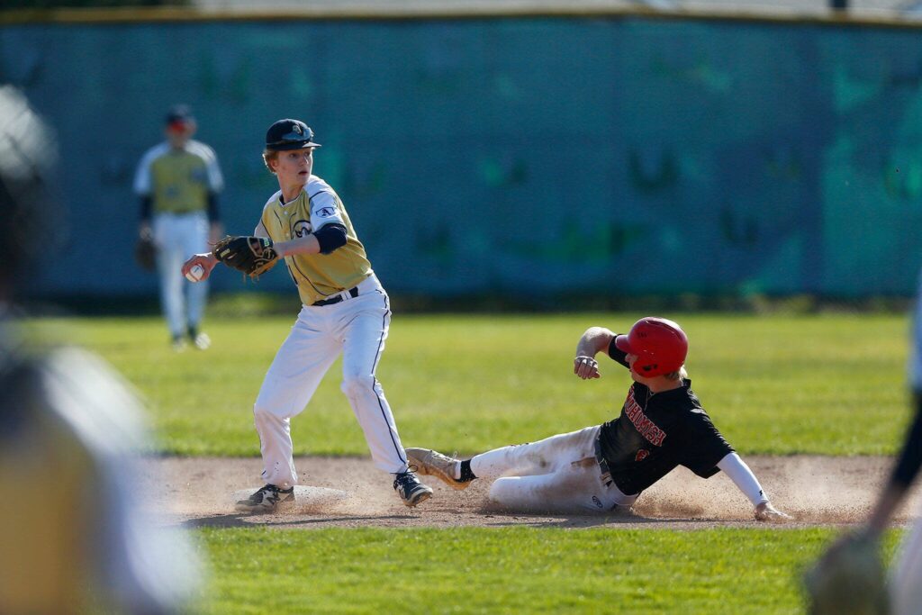 Arlington’s Reece Boekenoogen looks to turn a double play during a matchup against Snohomish on Friday, April 14, 2023, at Earl Torgeson Field in Snohomish, Washington. (Ryan Berry / The Herald)
