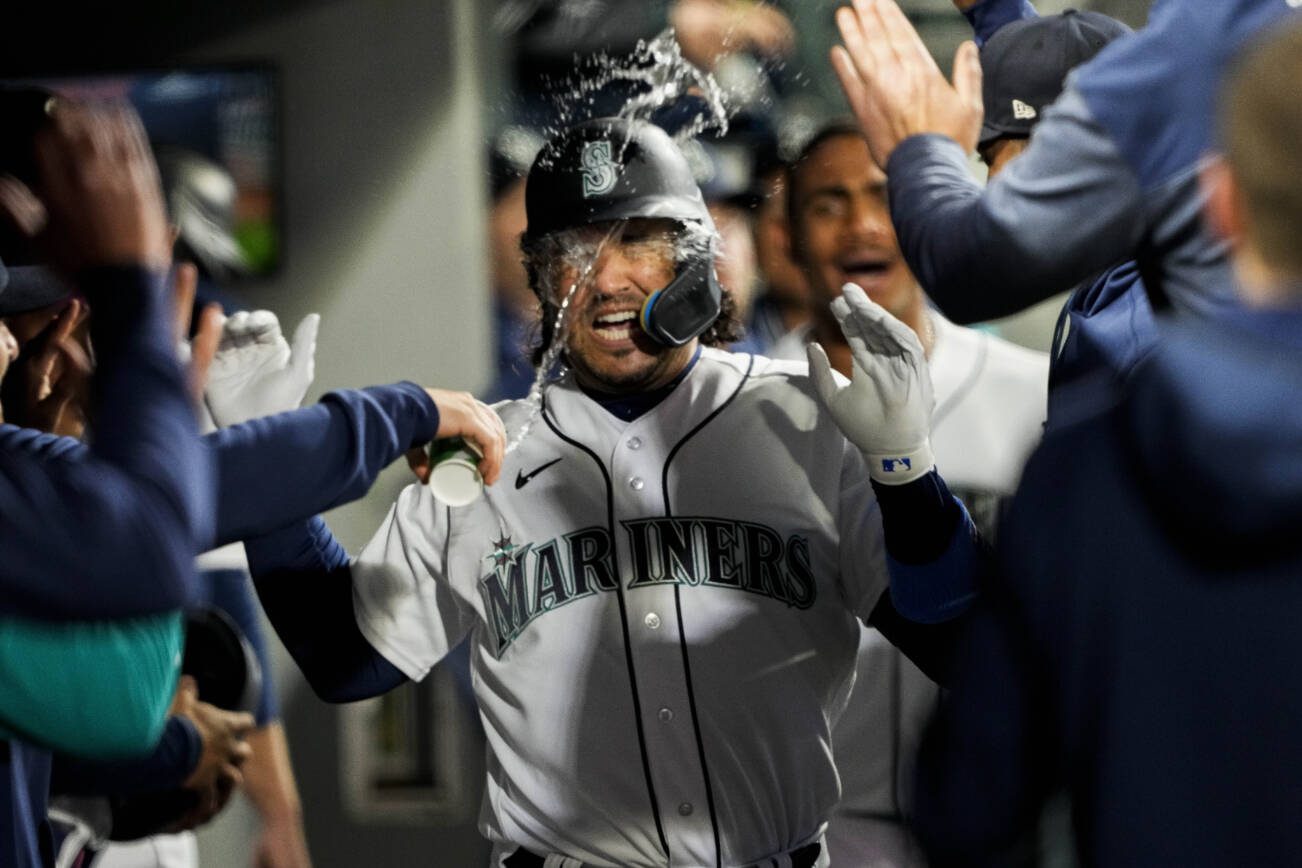 Seattle Mariners' Eugenio Suarez has water thrown at him in the dugout after his home run against the Colorado Rockies during the fourth inning of a baseball game Saturday, April 15, 2023, in Seattle. (AP Photo/Lindsey Wasson)