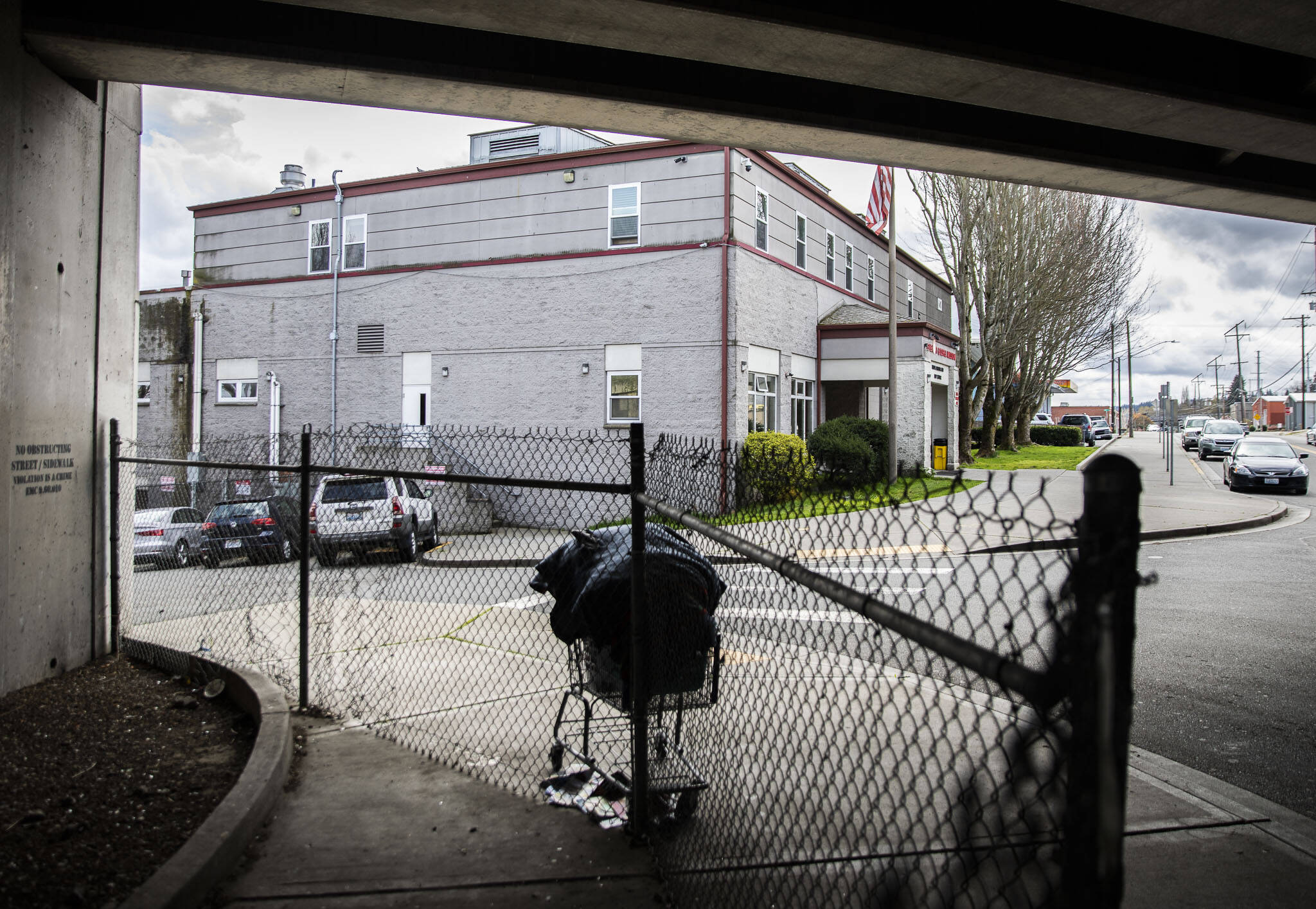 A shopping cart full of items is left unattended outside of the Everett Gospel Mission along a fence put in place due the current “no sit, no lie” ordinance on Tuesday, April 18, 2023 in Everett, Washington. (Olivia Vanni / The Herald)