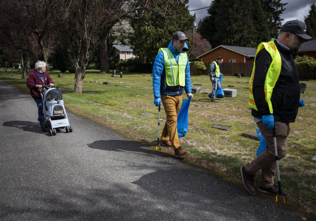 Volunteers walk through the Marysville Cemetery and pick up trash on Tuesday, April 18, 2023 in Marysville, Washington. (Olivia Vanni / The Herald)
