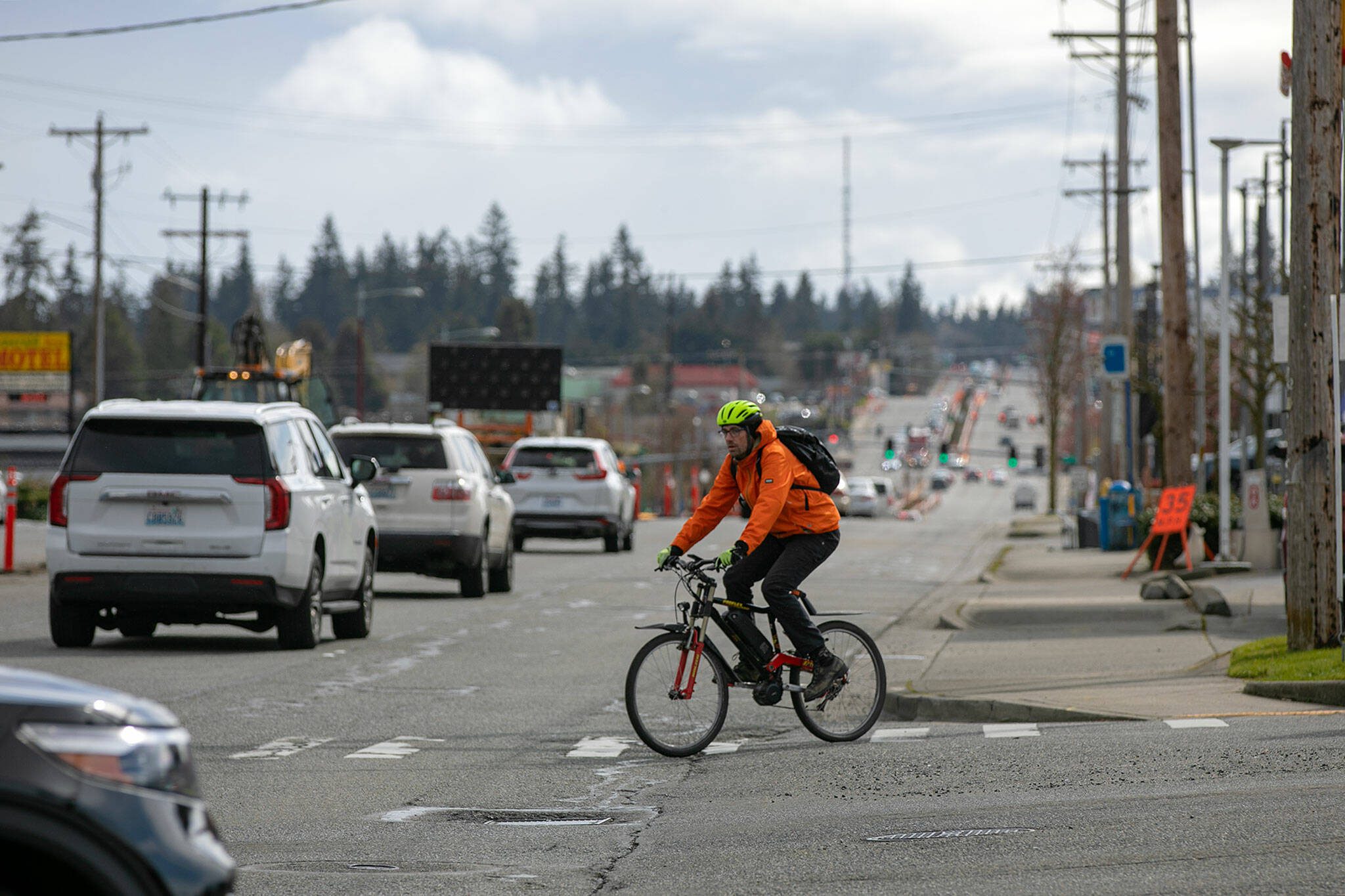 A cyclist crosses Highway 99 at 220th Street before riding south along the highway on Tuesday, April 18, 2023, in Edmonds, Washington. (Ryan Berry / The Herald)