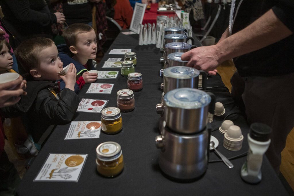 Rowan Ryan-Brock, left, and his brother Willow Ryan-Brock, right, both 4, sip on tea and hot chocolate samples during the Cascadia Tea spring festival at Floral Hall in Everett, Washington on Saturday, April 15, 2023. (Annie Barker / The Herald)
