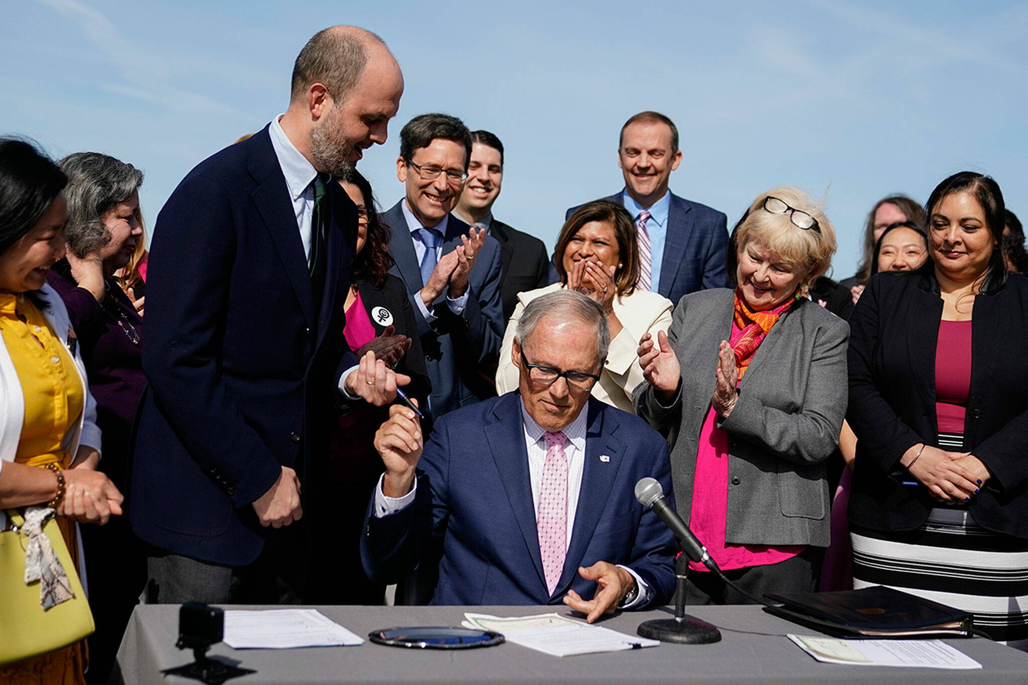 Washington Gov. Jay Inslee hands a pen to Rep. Drew Hansen, D-Bainbridge Island, left, after signing House Bill 1469, which shields abortion and gender-affirming care patients and providers from prosecution by out-of-state authorities and prevents cooperation with investigations, Thursday, April 27, 2023, at the University of Washington’s Hans Rosling Center for Population Health in Seattle. (AP Photo/Lindsey Wasson)