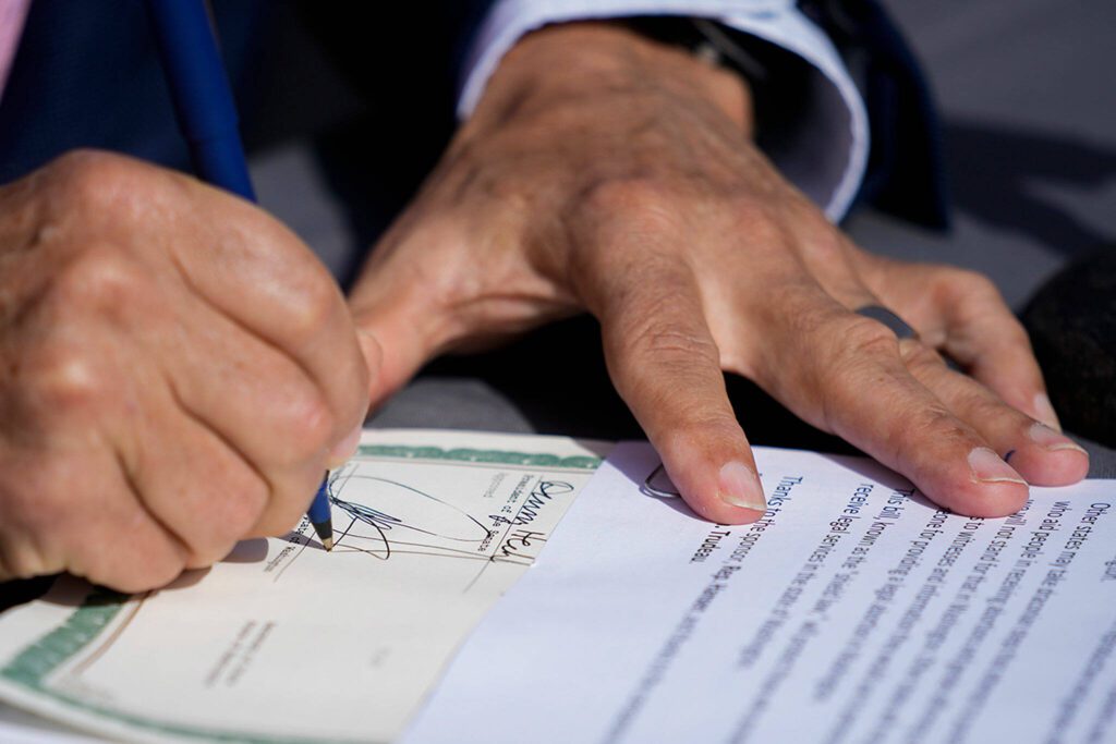 Washington Gov. Jay Inslee signs House Bill 1469, which shields abortion and gender-affirming care patients and providers from prosecution by out-of-state authorities and prevents cooperation with investigations, Thursday, April 27, 2023, at the University of Washington’s Hans Rosling Center for Population Health in Seattle. (AP Photo/Lindsey Wasson)
