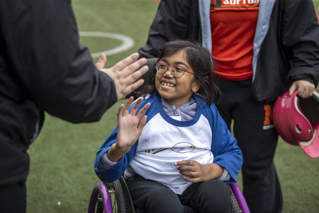 Ananya Raghavan, 10, gives a high-five during a game of YMCA’s Miracle League Baseball at Monroe Rotary Field in Monroe, Washington on Saturday, April 22, 2023. The program is designed to allow people with diverse abilities to play baseball. (Annie Barker / The Herald)
