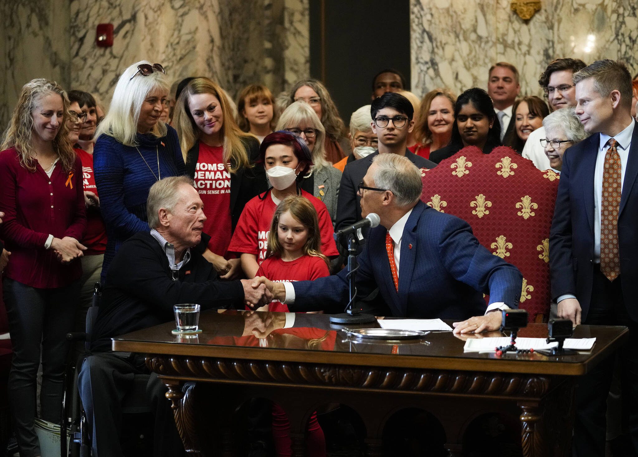 Washington Gov. Jay Inslee shakes the hands of Jim and Ann-Marie Parsons, in blue, whose daughter Carrie was killed in the 2017 Las Vegas shooting, after Inslee signed Senate Bill 5078, which ensures that firearms manufacturers and sellers will face liability if they fail to adopt and implement reasonable controls to prevent sales to dangerous individuals, Tuesday, April 25, 2023, at the Capitol in Olympia, Wash. (AP Photo/Lindsey Wasson)