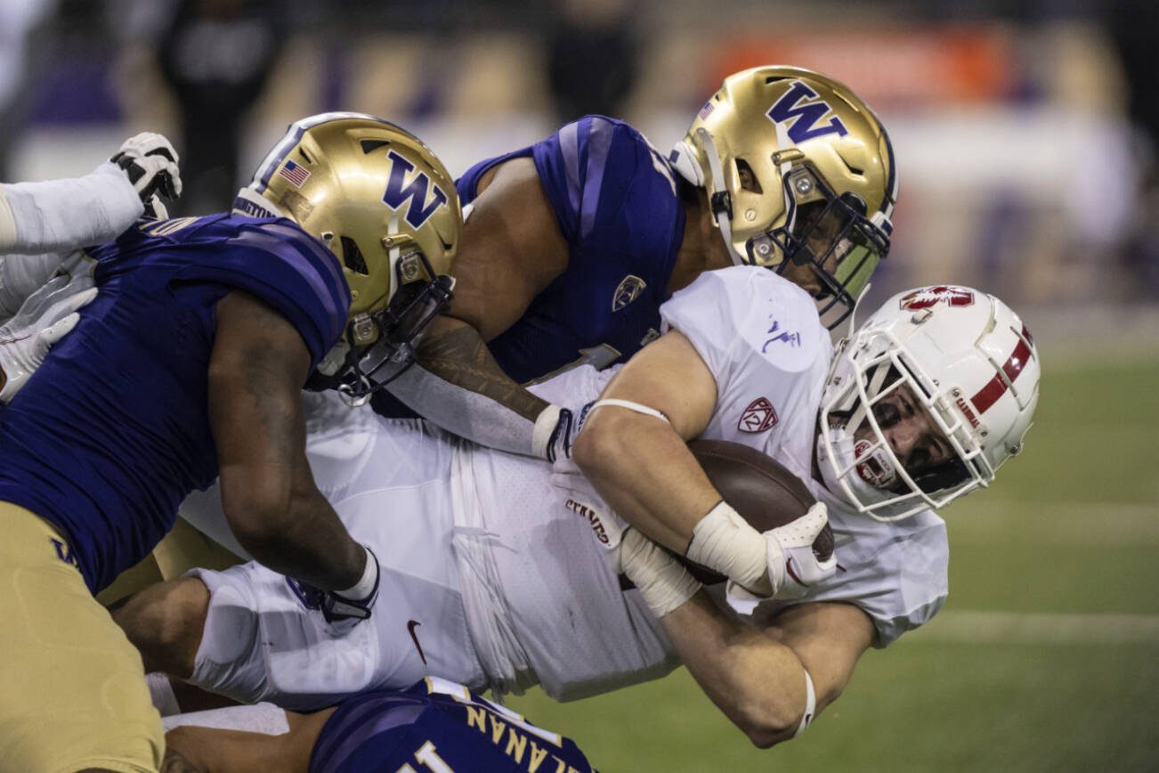 Stanford running back Casey Filkins dives for yardage while being tackled by Washington linebackers Dominique Hampton, left, and Alphonzo Tuputala, top, during the first half of an NCAA college football game Saturday, Sept. 24, 2022, in Seattle. (AP Photo/Stephen Brashear)