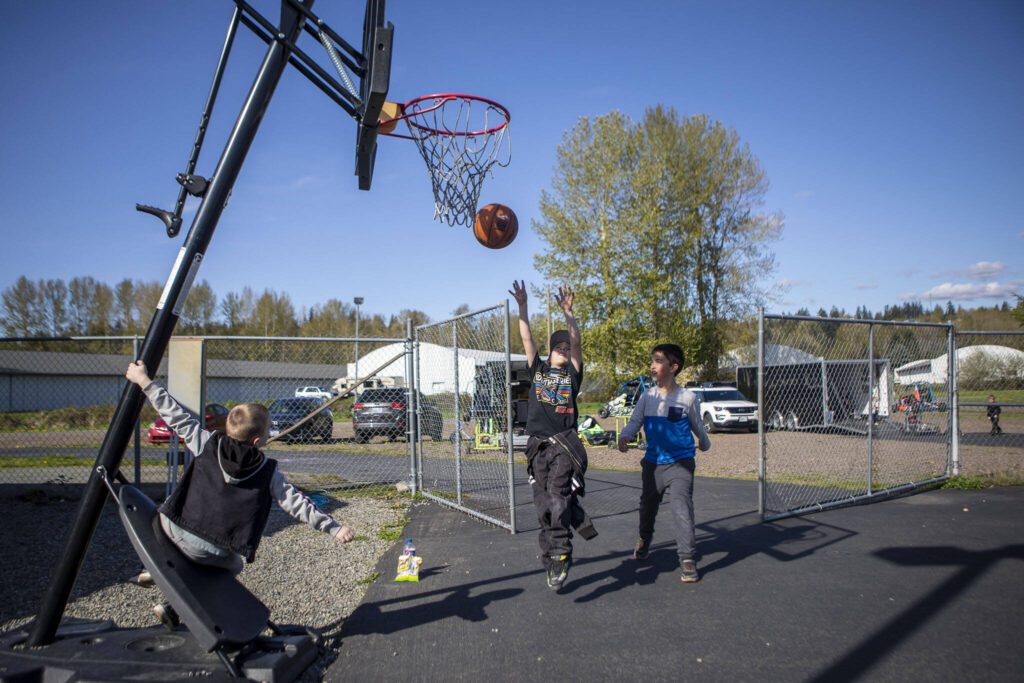 Left to right, Quinten Pollen, 9, Aiden Stone, 8, and Ryan Cannon, 9, play basketball at Evergreen Fairgrounds in Monroe, Washington on Tuesday, April 25, 2023. (Annie Barker / The Herald)
