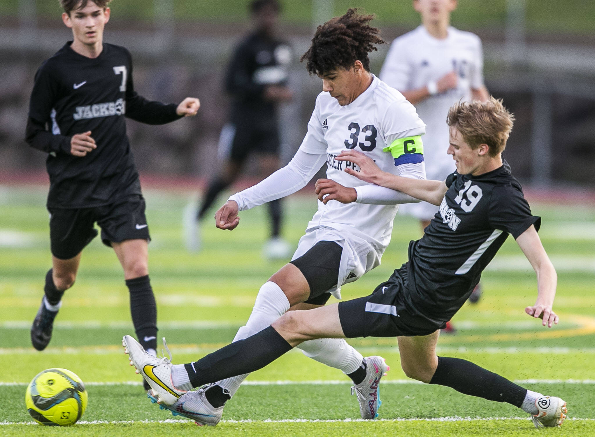 Glacier Peak’s Azavier Coppin is slide tackled by Jackson’s Sam Russel during the game on Friday, April 28, 2023 in Snohomish, Washington. (Olivia Vanni / The Herald)