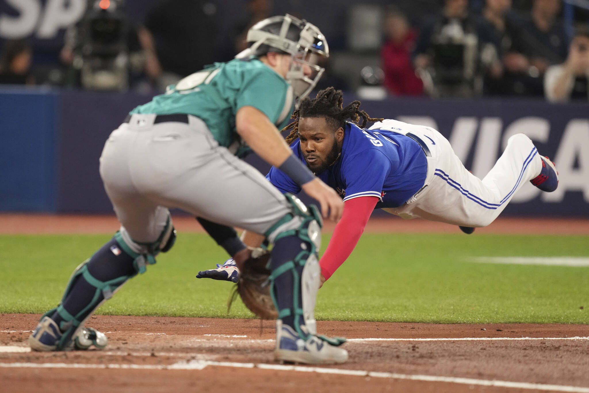 The Blue Jays’ Vladimir Guerrero Jr. dives home to score as Mariners catcher Cal Raleigh waits for the throw after a hit by Matt Chapman during the third inning of a game Friday in Toronto. (Chris Young/The Canadian Press via AP)